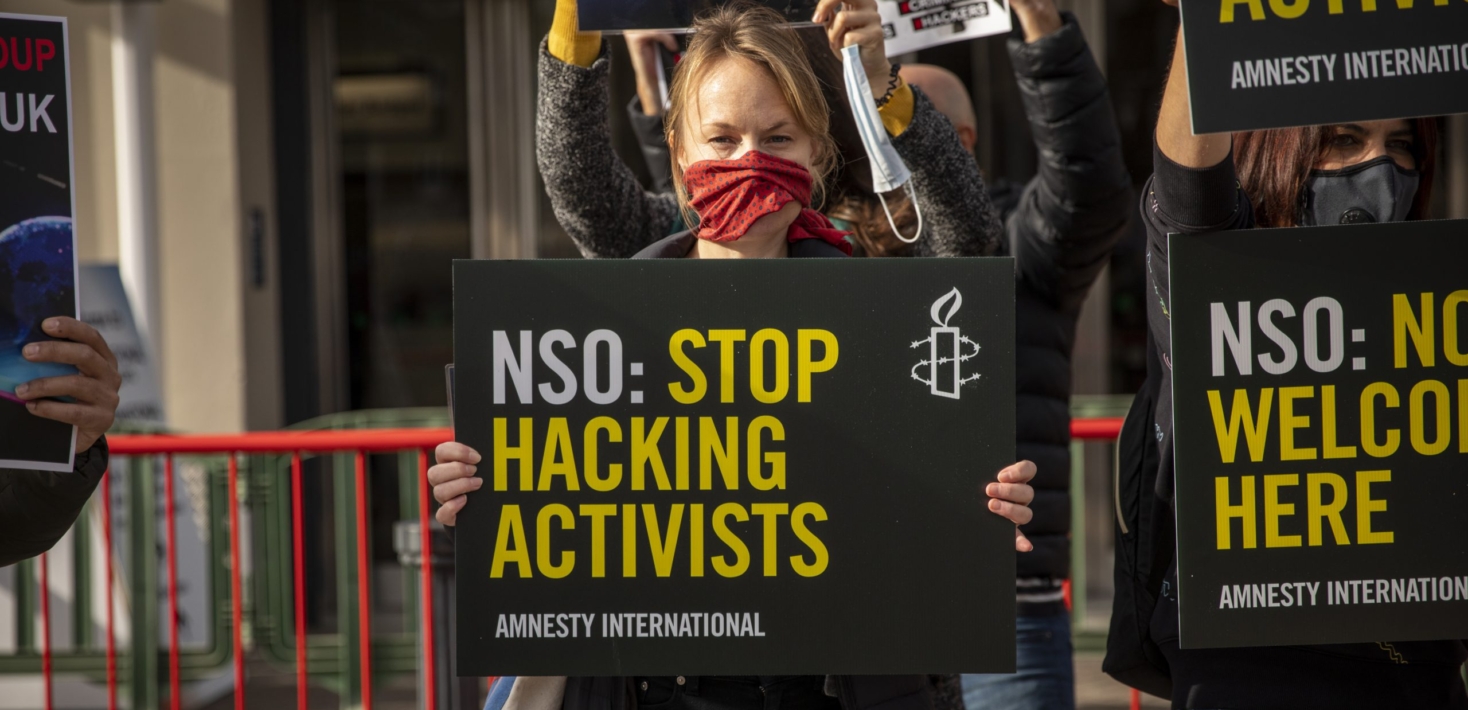 People at a protest holding signs with the words "NSO: stop hacking activists"